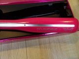 a pink curling iron in a pink box on a wooden table