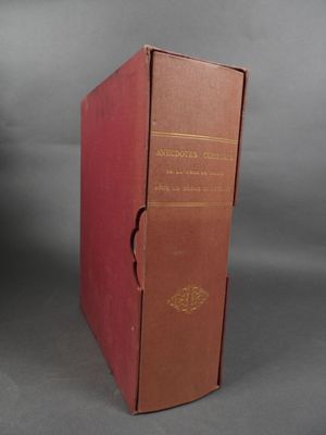 un vieux livre rouge posé sur une table près d'un mur gris