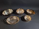 six silver plated bowls and a bowl on a black surface