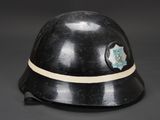 an old black helmet with a badge on it on a black background