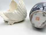 a white bird and a blue and white vase on a table