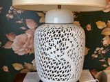 une lampe posée sur une table devant un papier peint à motifs floraux