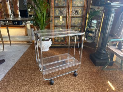 a glass trolley with a basket on top of it in a room