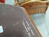 a brown suitcase sitting on the floor next to a wicker chair