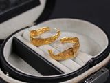 une paire de boucles d'oreilles en or dans un écrin posé sur une surface noire