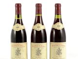 trois bouteilles de vin sont alignées sur une surface blanche