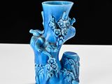 a blue vase with birds on it sitting on a table