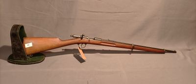 un vieux fusil avec un canon en bois sur un support sur fond blanc