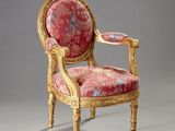 une chaise ancienne avec une assise rembourrée rouge et des finitions dorées
