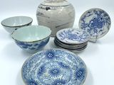 several blue and white plates and bowls sitting on a white surface
