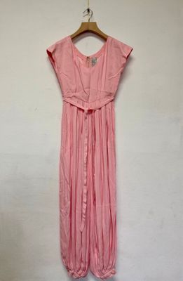 une robe rose suspendue à un cintre devant un mur blanc
