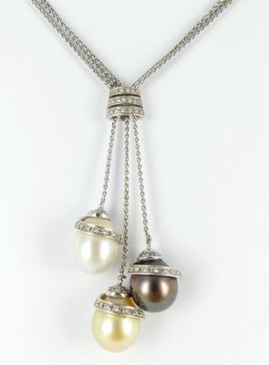 a close up of a necklace with three pearls hanging from it