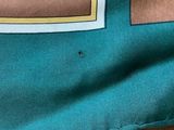 a close up of a teal colored shirt with a brown square on it