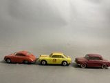 four toy cars are lined up in a row on a gray surface