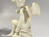 a statue of a little angel sitting on top of a table