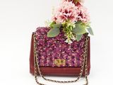 pink flowers are placed in a purple purse on a white background