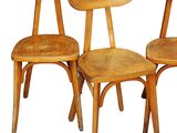 three wooden chairs sitting next to each other on a white surface