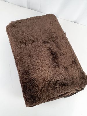 une serviette posée sur un lit aux draps blancs, avec des draps blancs en arrière-plan
