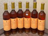 six bouteilles de vin posées les unes à côté des autres sur un tonneau