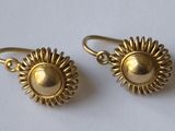 boucles d'oreilles plaquées or à motif « sunburst » sur un fond blanc