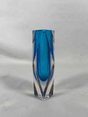 un vase en verre bleu posé sur une surface blanche