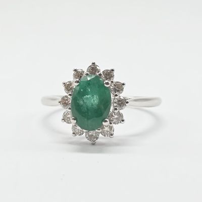 gros plan d'une bague avec une pierre verte entourée de diamants blancs