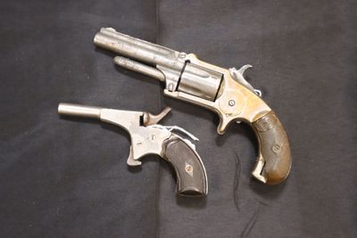 deux vieux revolvers posés sur un tissu noir, sur fond noir