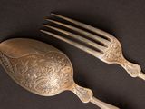 two silver spoons and a fork on a table