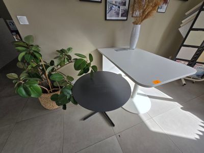 a white table with a black table top and a potted plant