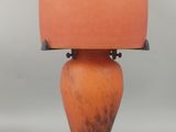 une lampe orange avec un abat-jour vert posée sur une table