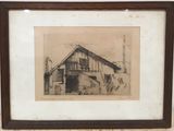 un vieux dessin représentant une grange, encadré et posé sur une table