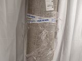 a roll of burlock fabric wrapped in plastic on a bed