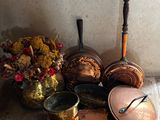 des casseroles et des poêles sont posées par terre à côté d'un vase de fleurs