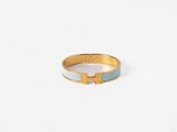 une bague dorée et bleue sur laquelle figure la lettre « h »