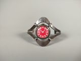 une bague en argent sur laquelle est gravée une horloge rouge