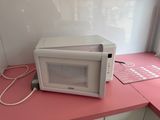 a microwave sitting on a pink counter top next to a window