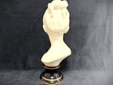 a white bust of a woman sitting on top of a blue and white vase