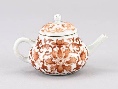 une théière orange et blanche surmontée d'un oiseau
