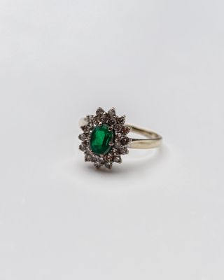 gros plan d'une bague avec une pierre verte entourée de diamants blancs