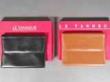 pair of black and tan leather wallets on display in a pink box