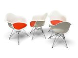 three white and orange chairs sitting next to each other on a white surface