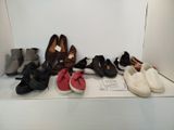 Plusieurs paires de chaussures sont alignées sur une étagère devant un mur blanc