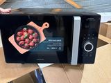 a woman holding a microwave that is sitting on a table