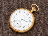 un gros plan d'une montre de poche posée sur un tissu