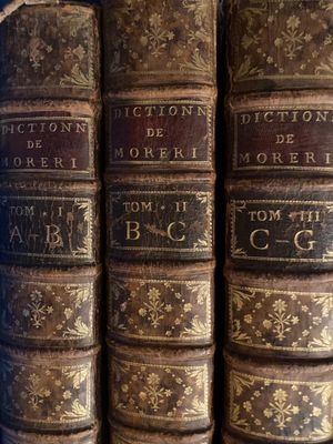 several old books are stacked on top of each other on a shelf