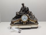 une statue d'un homme assis au sommet d'une horloge