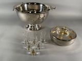 a silver bowl and glasses on a table next to a silver container