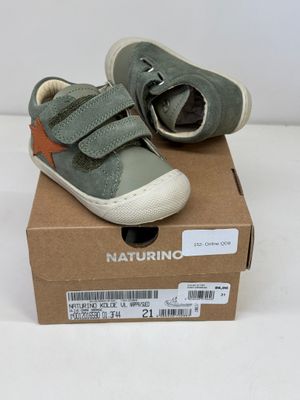 des chaussures de petit garçon dans une boîte posée sur une surface blanche