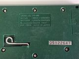 a close up of a green electronic device on a white surface