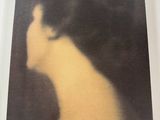 On voit l'arrière d'une photo représentant la tête d'une femme, encadrée dans un cadre blanc.